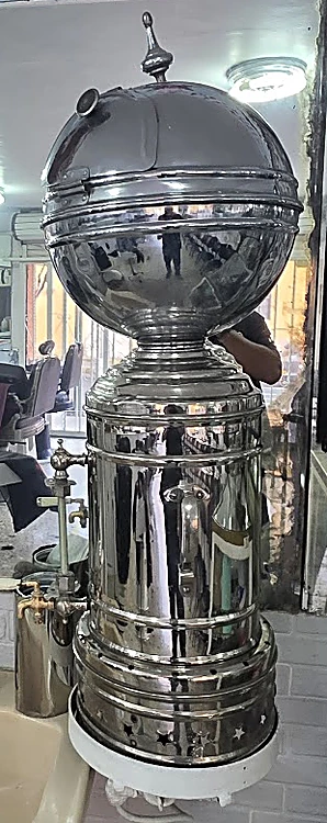 Esterilizador cromado en forma de globo sobre una base cilíndrica, junto al lavabo