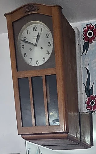 Reloj de pared de péndulo en caja de madera con carátula blanca de números arábigos